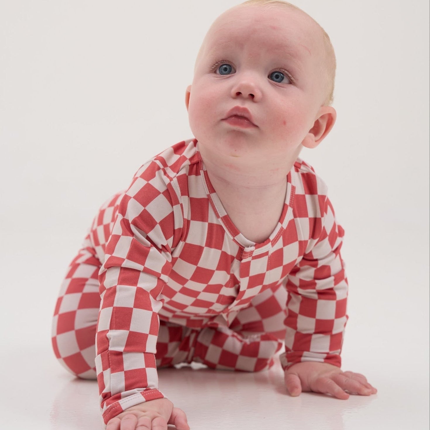 Baby wearing a red and white checkered outfit on a white background
