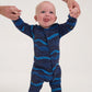 Baby wearing a blue wave-patterned onesie standing on a white background