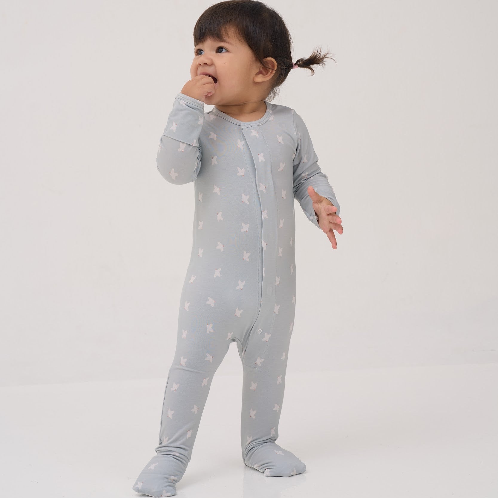 Child wearing a gray onesie with white patterns on a light gray background