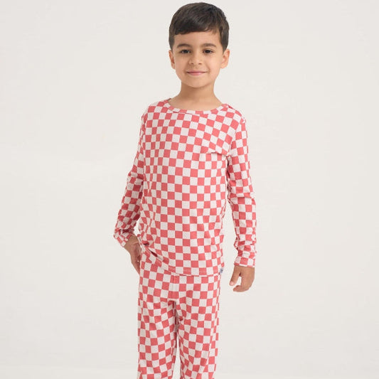 Child wearing a red and white checkered pajama set on a white background